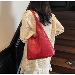 Macro detail of red woven leather tote bag texture and wide shoulder strap on model