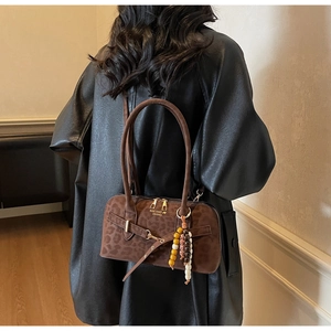 Detail of leopard print suede handbag with long strap and wooden bead tassel charm
