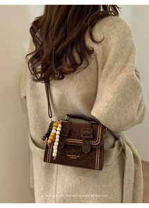 Detail of leopard print crossbody bag with colorful wooden bead tassel charm on coat