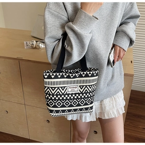 Detail of canvas tote bag featuring geometric black and white patterns and brand label