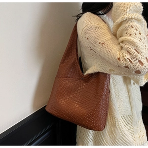 Close-up of caramel brown woven tote bag with magnetic snap and wide shoulder strap