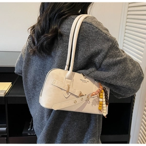 Detail of beige leather crossbody bag with colorful bead charm and metal buckle