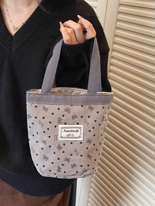 Grey corduroy tote bag with bow and heart prints held by a model for daily use