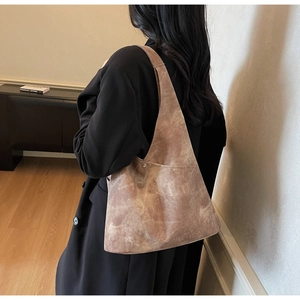 Brown vintage textured large capacity hobo bag worn over shoulder with black coat