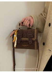 Detail of leopard print handbag with gold studs and decorative beaded charm accessory