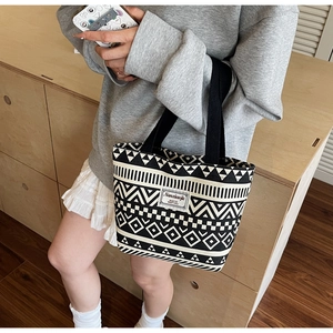 Close-up of the geometric pattern canvas tote bag with black strap handles and woven label