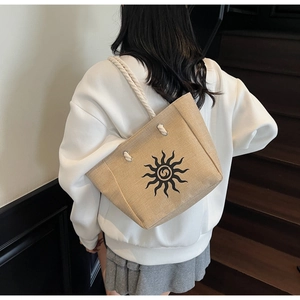 Detail of beige linen tote bag featuring a sun print and braided cotton rope handles