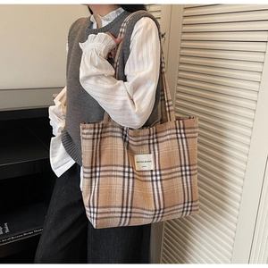 Detailed view of checkered tote bag with woven label worn by a model in casual setting