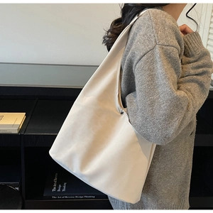 Detail of minimalist beige hobo bag with wide strap and silver studs on leather