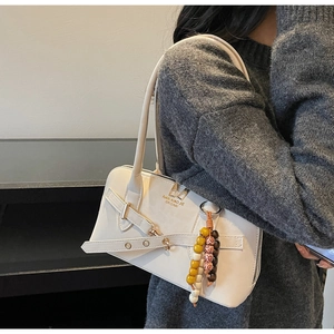 Detail of off-white leather shoulder bag with zipper and ethnic beaded charm accessory