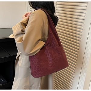 Detail of burgundy leopard embossed hobo bag with wide strap on khaki trench coat