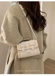 Detail of minimalist retro crossbody bag with contrast stitching and branded lettering