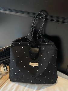 Large mesh floral shoulder bag with woven rope handles and brand label on a desk