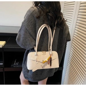 Detail of cream PU leather handbag with beaded pendant and brand text on back view
