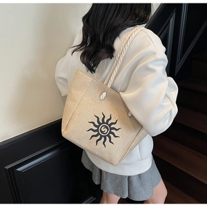 Detail view of large linen tote bag with sun print and white rope handles on shoulder