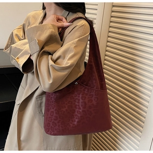 Macro view of burgundy leopard embossed suede tote bag with metallic snap button closure