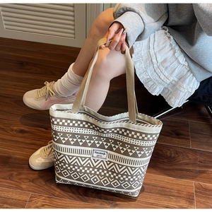 Detail of canvas tote bag with brown tribal geometric patterns and a woven logo patch