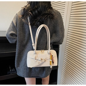 Detail of beige crossbody bag featuring belt buckle design and wooden bead tassel