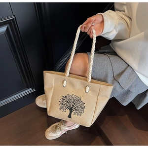 Detail of beige linen tote bag featuring black tree silhouette and white rope handles