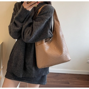 Detail of light brown woven tote bag showing premium leather texture and metal snap closure