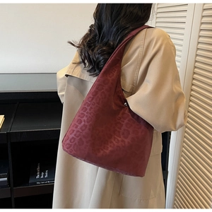 Detail of burgundy leopard print hobo bag worn with a beige trench coat for work
