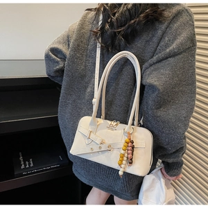 Close-up of a cream leather handbag with decorative beads and metal buckle details