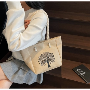 Linen bucket tote with tree print and cotton rope handle carried on a wooden staircase