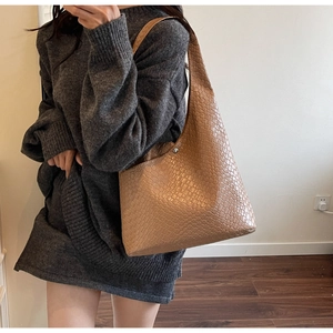Detail view of large brown woven leather hobo bag worn over the shoulder with wide strap