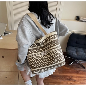 Detail of canvas tote bag featuring ethnic geometric patterns and beige shoulder strap