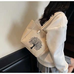 Linen tote bag with black tree print and cotton rope handle worn by a model