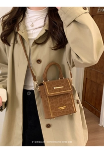 Detail of leopard print handbag with gold studs and brand logo on beige trench coat