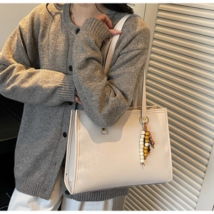 Detail of off-white tote bag with leopard print bead tassel and smooth leather texture