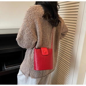 Detail of red woven bucket bag showing intricate cross-weave texture and flap closure