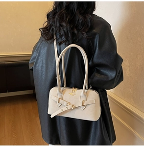 Detail of a beige leather crossbody bag with decorative gold buckle on a model