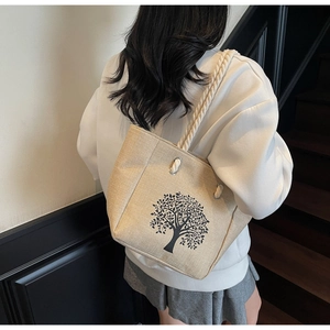 Detail of linen tote bag featuring a black tree print and thick woven cotton rope handles