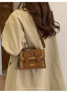 Detail of retro leopard print crossbody bag with gold studs on a model in a trench coat