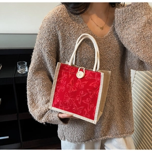 Detail of red butterfly embroidery on a rustic linen handbag with braided handles