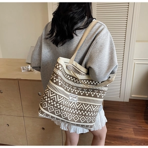 Detailed view of canvas tote bag with brown ethnic geometric patterns and brand tag