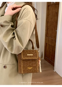 Detail of leopard print crossbody bag with gold rivets on light green trench coat