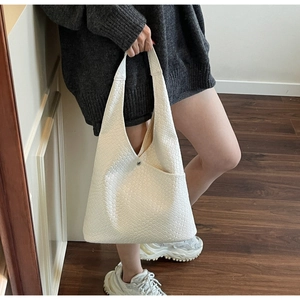 Detailed view of the intricate white woven texture and metal clasp on this tote bag