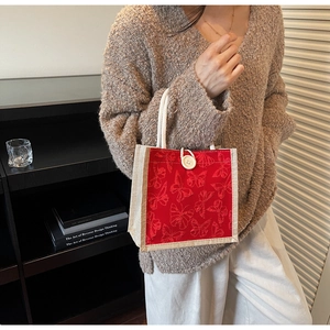 Detail of red canvas tote bag featuring butterfly patterns and white rope handles