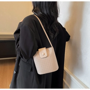 Detail of beige woven texture bucket bag styled with a black casual blazer for women
