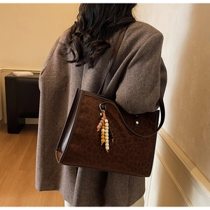 Detail of leopard print tote bag with beaded pendant and textured shoulder strap