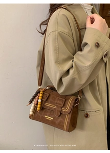 Detail of vintage brown crossbody bag with colorful bead charm and shoulder strap