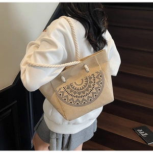Detail of beige linen tote bag with black mandala pattern and rope handle shown on stairs