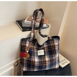 Detail of large plaid tote bag with classic check pattern and plush pompom charm