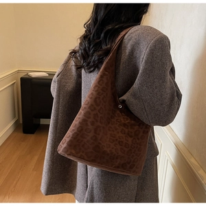 Detailed view of large brown leopard print suede tote bag worn on shoulder by model