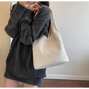 Close-up of white woven leather tote bag featuring signature intrecciato weave on model