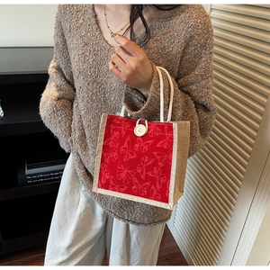 Detail of red butterfly embroidery on canvas tote bag with woven handles and button