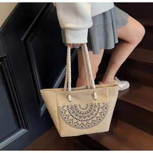 Close-up of bohemian jute bucket bag featuring black geometric sun pattern and cotton rope